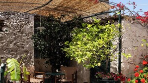 Une terrasse extérieure avec des murs en pierre, des meubles en bois et des plantes en pot.