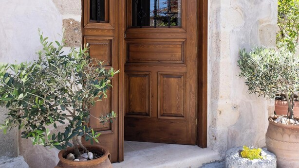 Un bâtiment en pierre avec une porte en bois, des plantes en pot et une lanterne au-dessus de la porte.