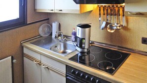 Een kleine keuken met een spoelbak, fornuis en koffiezetapparaat.