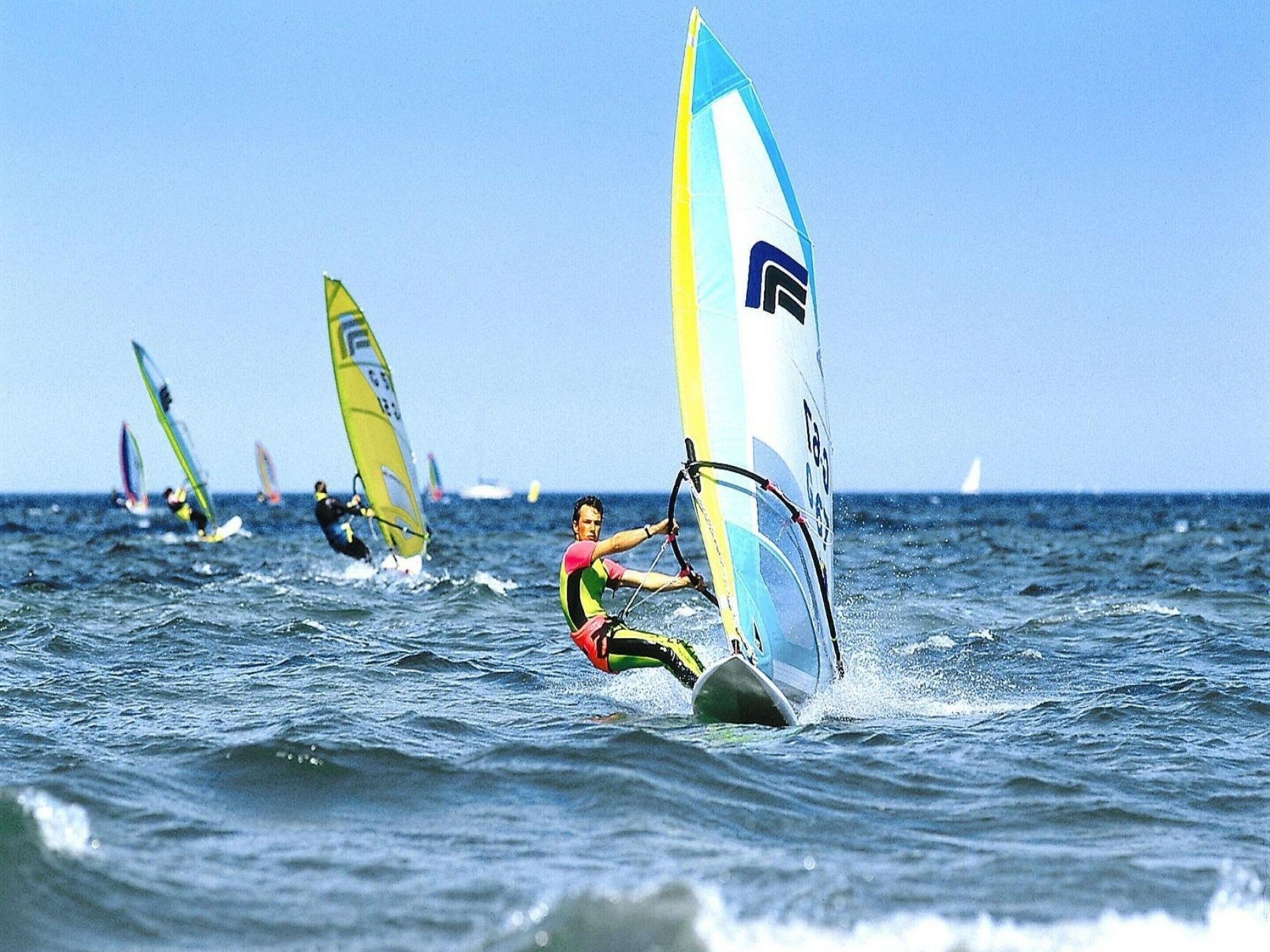 A group of windsurfers on a body of water.