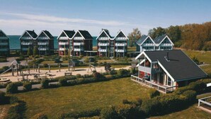 A row of modern, multi-story buildings with a central open space featuring playground equipment. - Tolles Ferienhaus fur Familien (Rechlin)
