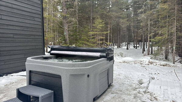 Un jacuzzi en un paisaje nevado de bosque.