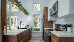 A modern kitchen with wooden cabinets, a stainless steel refrigerator, and a built-in oven.