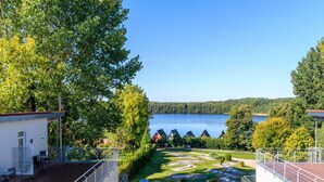 En vy över en fastighet vid sjön, med en träterrass, en liten byggnad och fri utsikt över sjön.