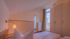 Ett hotellrum med en säng, ett nattduksbord, en lampa, ett element och utsikt över omgivningarna.
