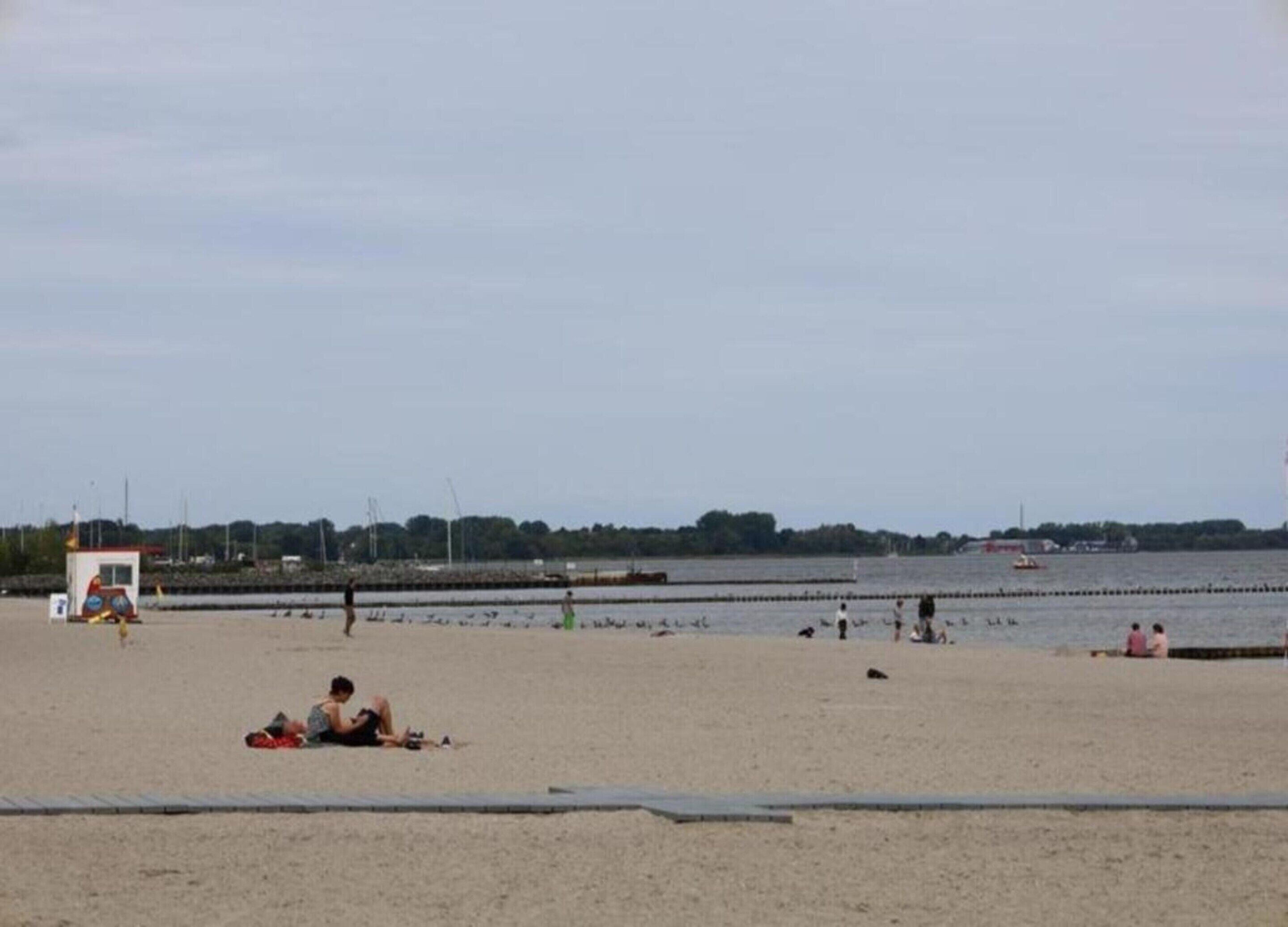 Ein Strand mit einem Rettungsturm, sandigem Ufer und ruhiger See.