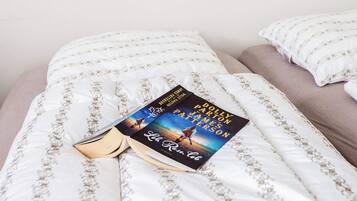 Un libro con el título 'La Reine Rouge' sobre una cama con ropa blanca y una almohada.