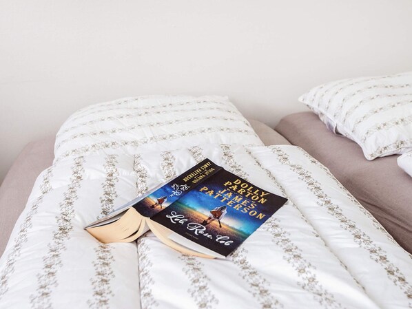 Un livre intitulé « La Reine Rouge » est posé sur un lit avec une literie blanche et un oreiller.