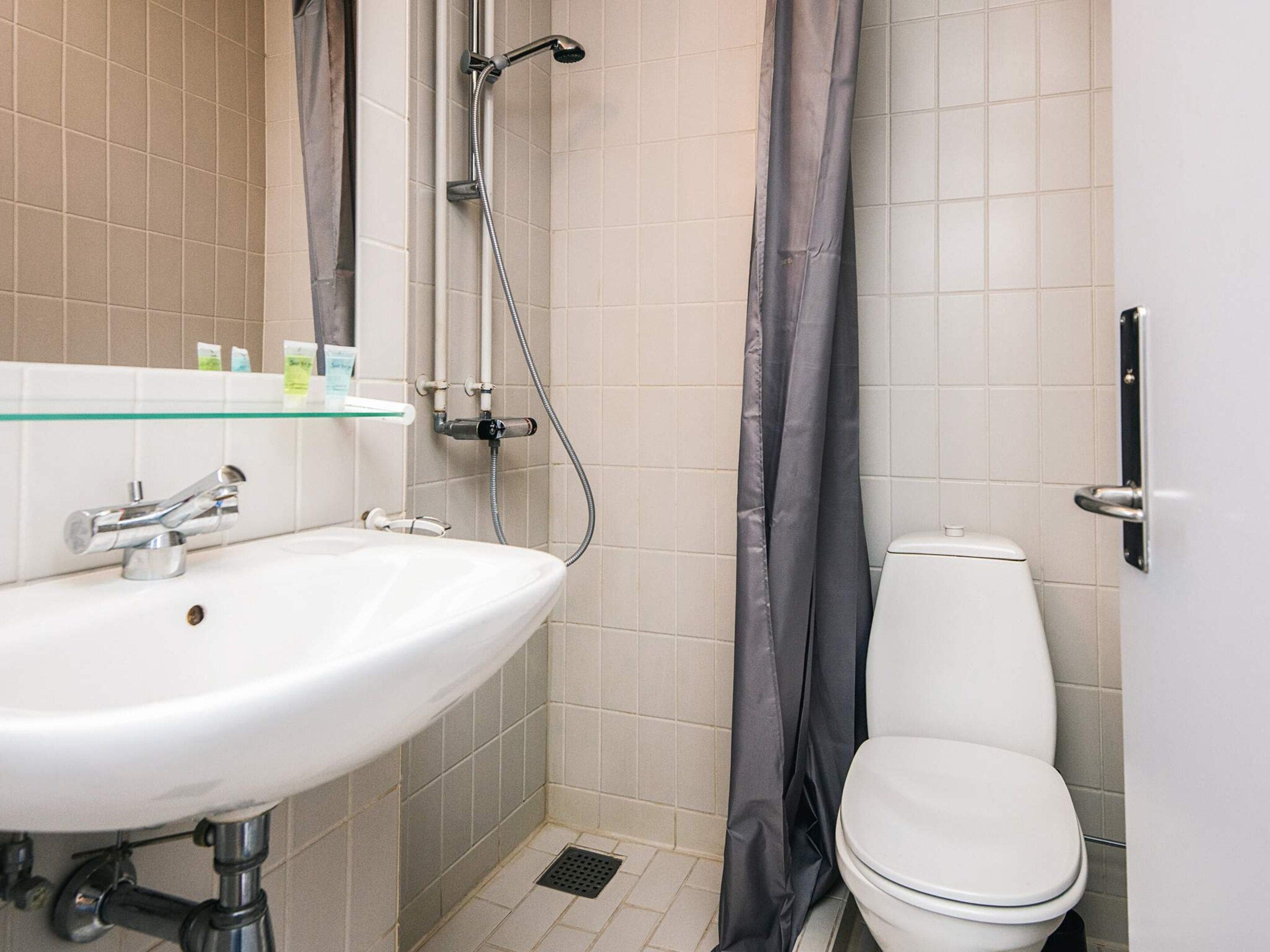 Une salle de bain avec un lavabo blanc, des toilettes et une douche avec un rideau.