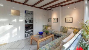 A living room with a wooden coffee table, a patterned sofa, and a bookshelf. - Orchis4 Bungalow Near Dunes in Julianadorp (Julianadorp)