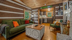 A cozy log cabin interior with a green sofa, wooden coffee table, and rustic decor.