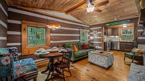 A log cabin interior with a dining area, sofa, and kitchen.