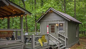 A rustic cabin with a wooden deck, a small porch, and a staircase leading to the entrance.