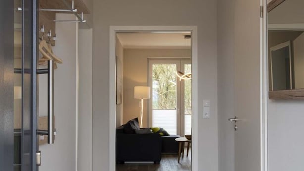 A hallway leading to a living area with a sofa, a table, and a lamp.