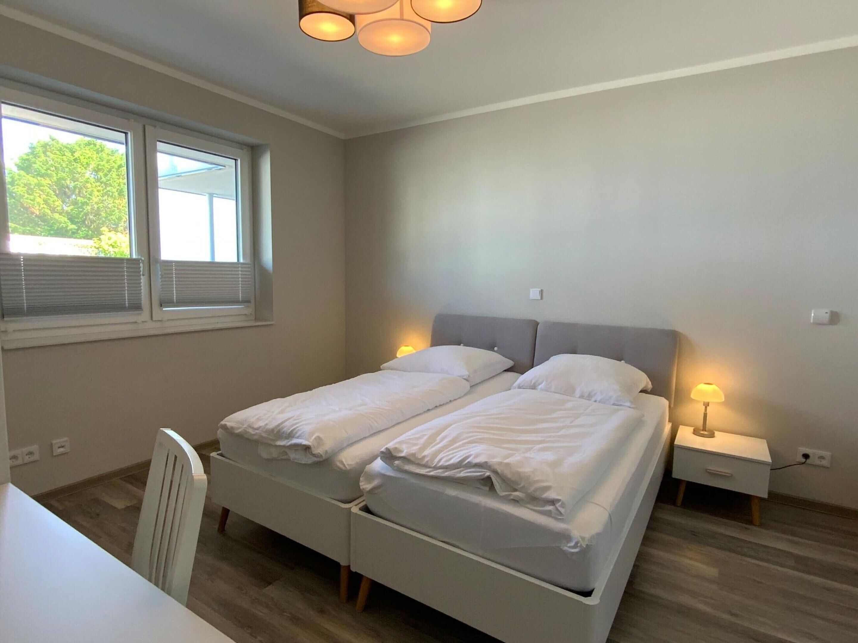 A bedroom with a double bed, bedside tables, a desk, and a chair.