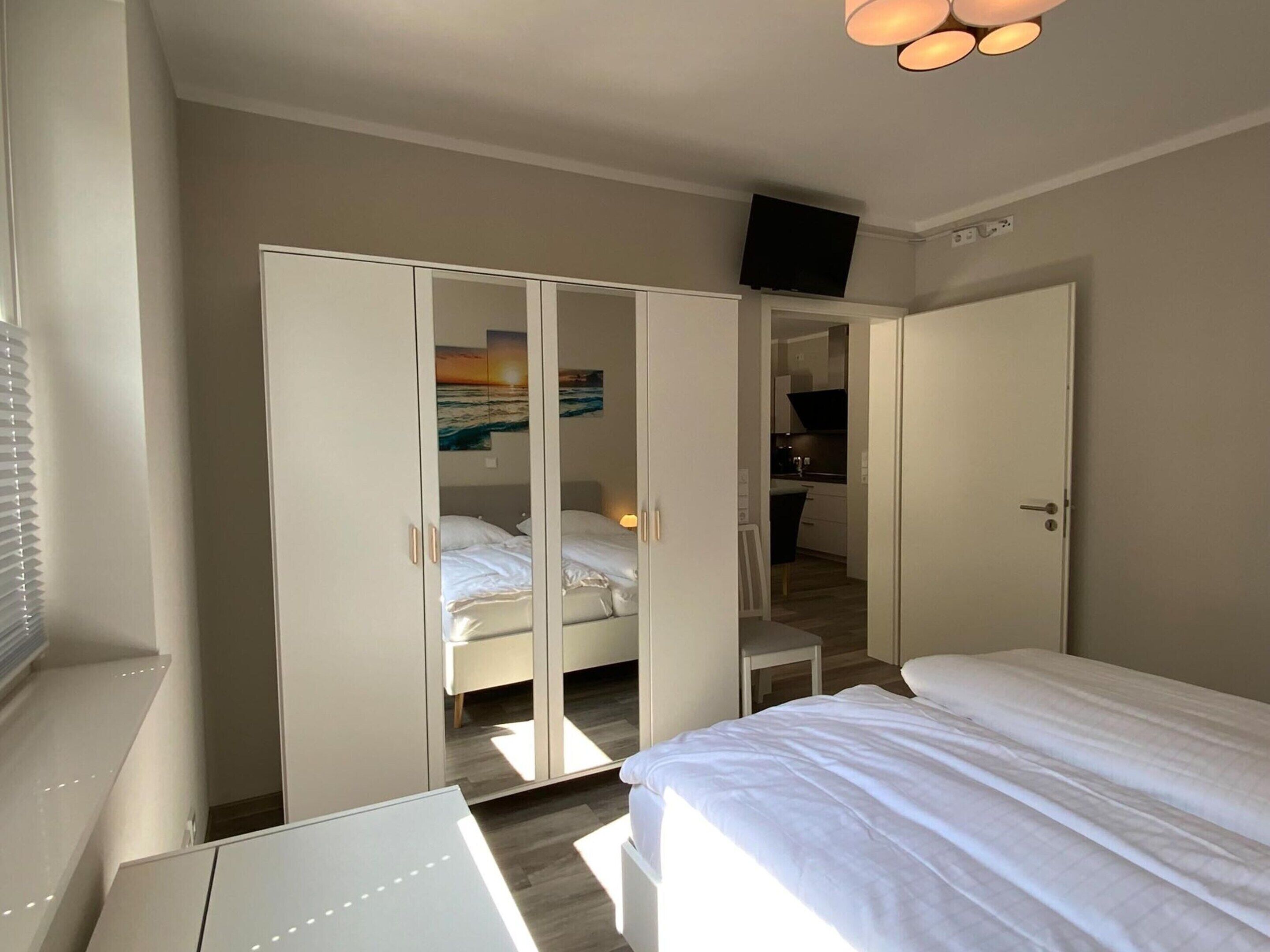 A bedroom with a bed, a wardrobe, and a TV mounted on the wall.