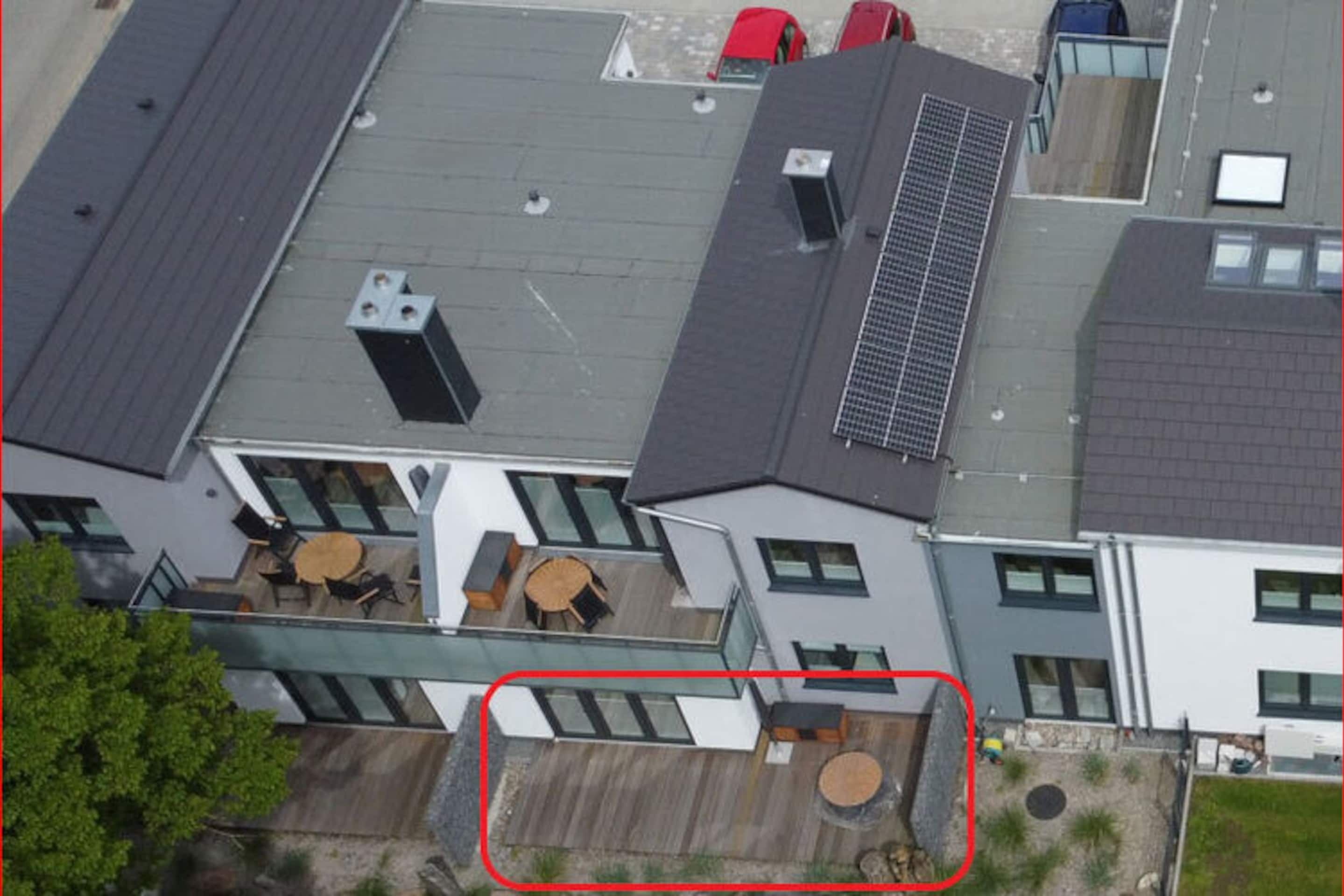 Moderni rakennus, jossa on tasakatto, suuret ikkunat ja kattoterassi, jossa on ulkokalusteita.