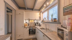 A modern kitchen with white cabinetry, a built-in oven, a sink, and a toaster. - Ferienhaus im Ferienpark Mueritz (Rechlin)