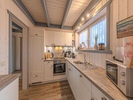 Una cocina moderna con armarios blancos, horno empotrado, lavamanos y tostadora.