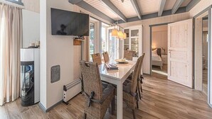 A modern kitchen with a dining area, wooden floors, and a TV mounted on the wall. - Ferienhaus im Ferienpark Mueritz (Rechlin)