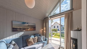 A modern living room with a sectional sofa, a coffee table, and a painting on the wall. - Ferienhaus im Ferienpark Mueritz (Rechlin)
