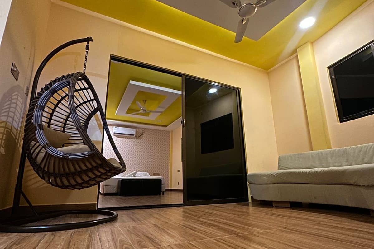 A modern living room with a hanging chair, a sofa, and a ceiling fan.