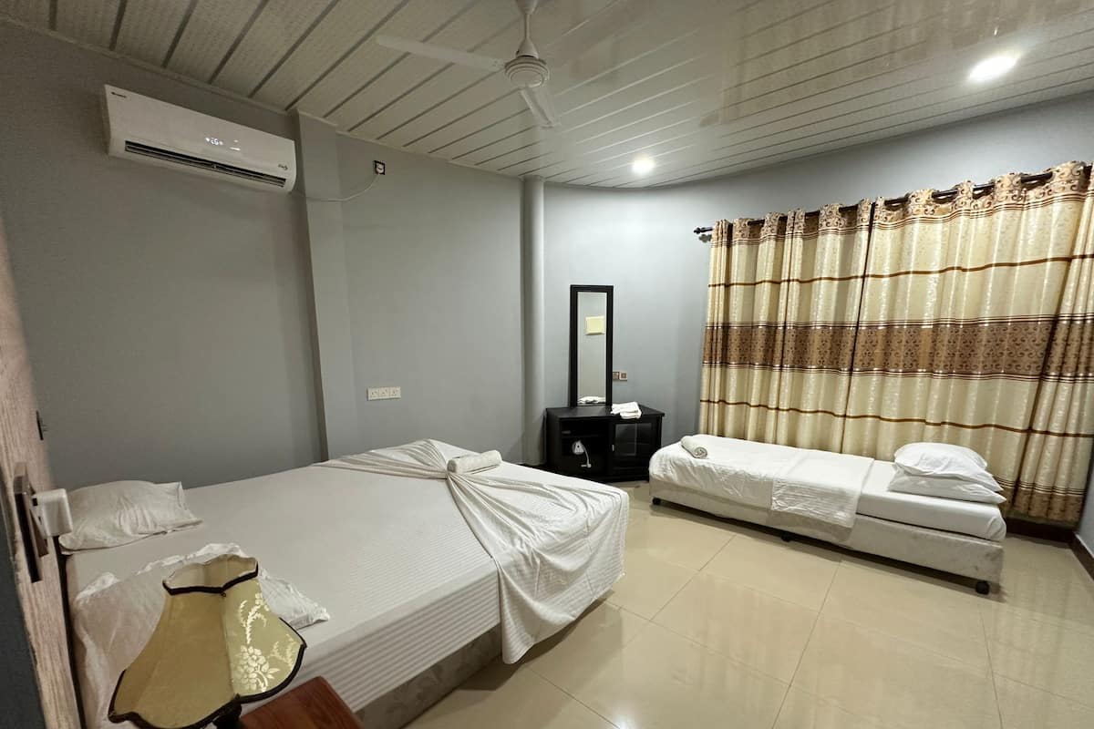 A hotel room with two single beds, a bedside table with a lamp, a mirror, and a curtain.