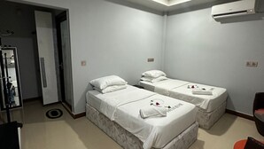 A hotel room with two beds, a ceiling fan, an air conditioning unit, and a small seating area. - NikainnHimandhoo (Himandhoo)