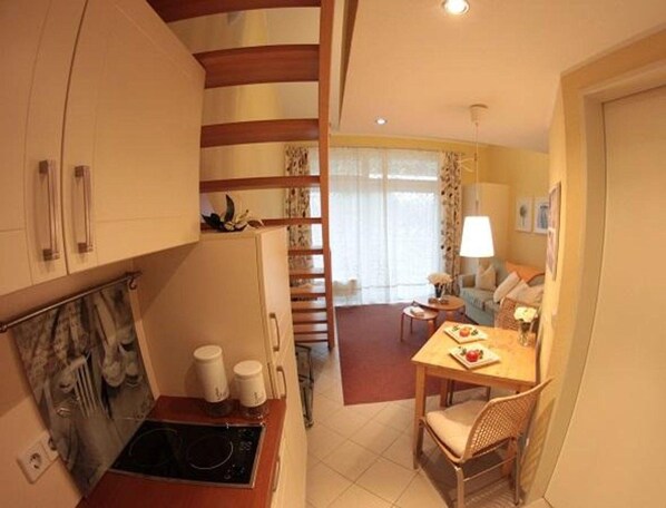 A compact living space with a kitchen, dining area, and a staircase leading to an upper level.