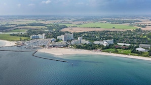 An aerial view of a coastal resort with multiple hotel buildings, a marina, and a beach. - Blockhaus im Ostseeresort Dampland (Damp)