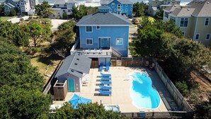 A residential area with a swimming pool, a house with a balcony, and a view of the ocean.
