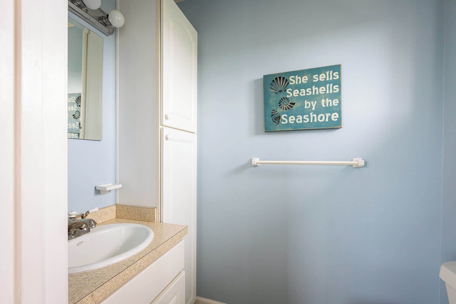 Une salle de bain équipée d’un lavabo, d’un miroir, d’un porte-serviettes et d’un panneau mural.