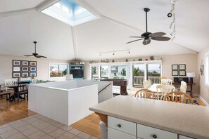 A spacious kitchen with a central island, a dining area, and a view of the outdoors. - Semi-Oceanfront w/ Heated Pool & Cabana (Corolla)