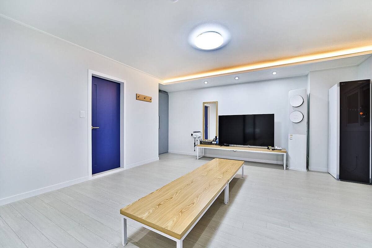 A modern living room with a wooden bench, a flat-screen TV, and a built-in bench with a mirror.