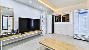 A modern hotel room with a flat-screen TV, a minibar, a minibar fridge, a wooden bench, and a minibar refrigerator. - Gimcheon Sweet Hotel (Gimcheon)