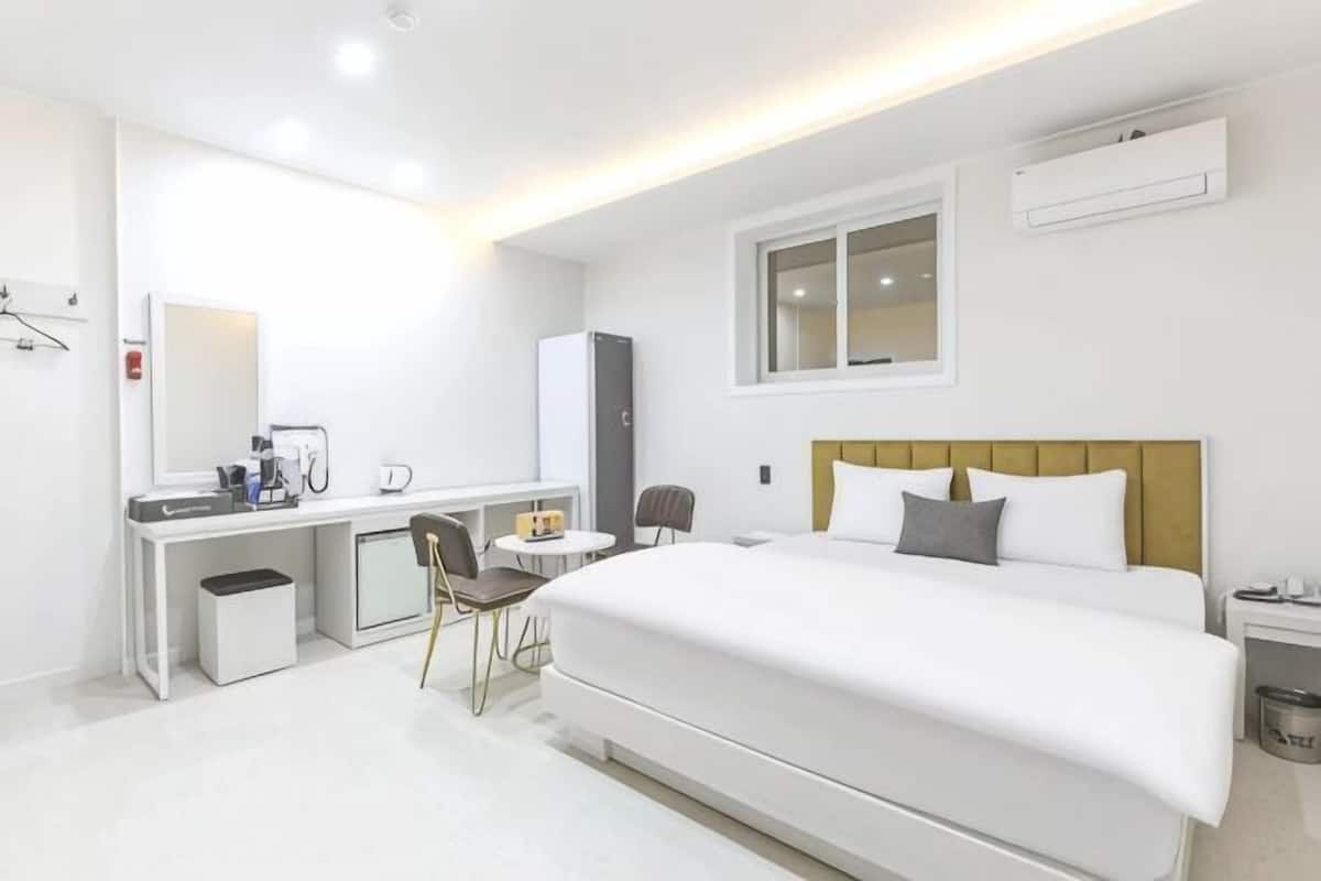 A hotel room with a bed, desk, chair, and a small table.