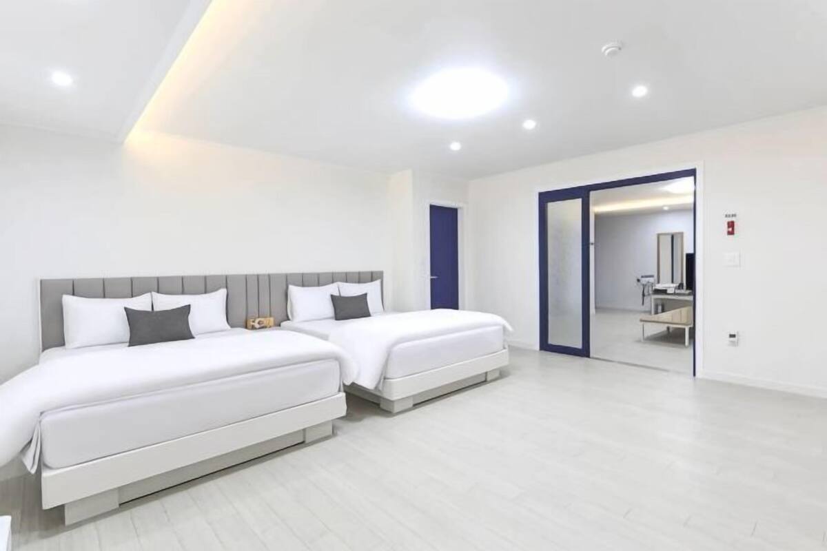 A modern hotel room with two beds, a bathroom, and a mirror.