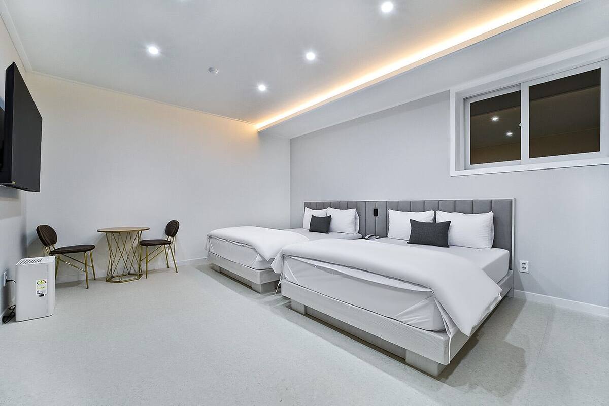 A modern bedroom with two beds, a small table, and two chairs.