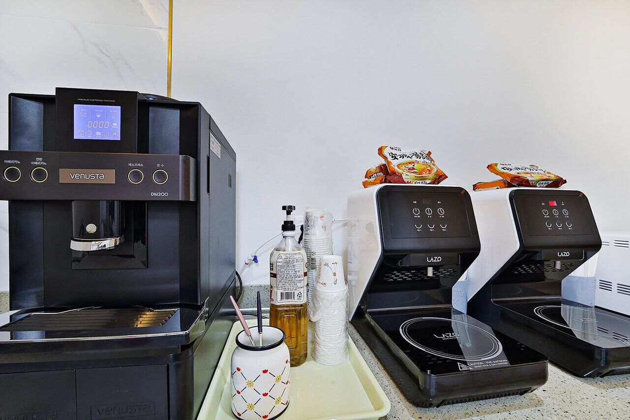 A coffee station with two espresso machines, a water dispenser, and a tray with cups, a bottle, and a mug.