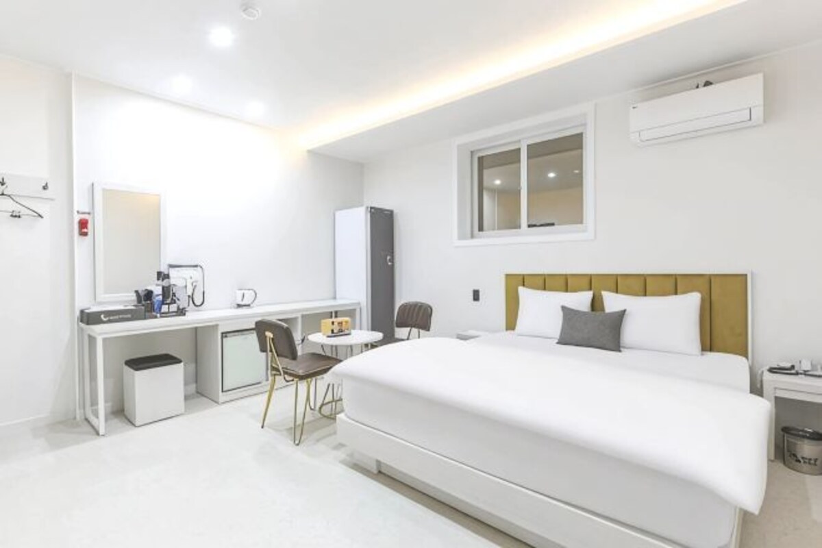 Una camera d'albergo con un letto, una scrivania, una sedia e un piccolo tavolino.