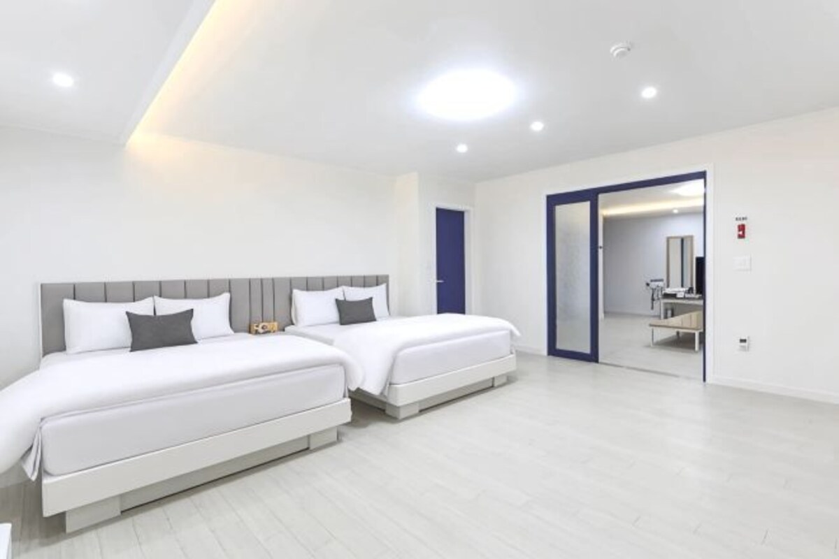 Una camera d'albergo moderna con due letti, un bagno e uno specchio.