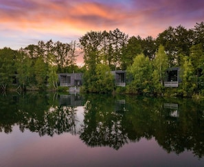 A tranquil lakeside setting with two wooden cabins surrounded by dense forest. - Lakeside Luxury Mansion (Antoing)