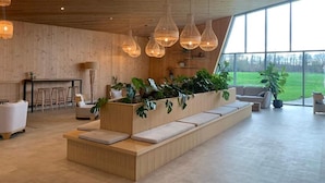 A modern interior with a long bench seating area, wooden ceiling, and large windows offering a view of the outdoors. - Lakeside Luxury Mansion (Antoing)
