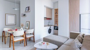 Ett modernt vardagsrum med en matplats, en soffa, ett soffbord och ett kök med tvättmaskin.