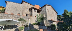 A stone building with multiple windows and a balcony, surrounded by greenery. - Stone House in Chiatri With Lake Views (Lucca)