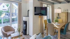 A modern living room with a large TV, comfortable seating, and a dining area. - Ferienhaus im Skandinavischen Stil (Rechlin)