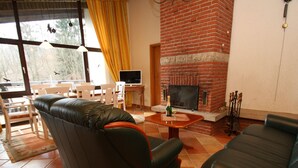 Un soggiorno con camino, divani in pelle, un tavolo da pranzo con sedie e una televisione.