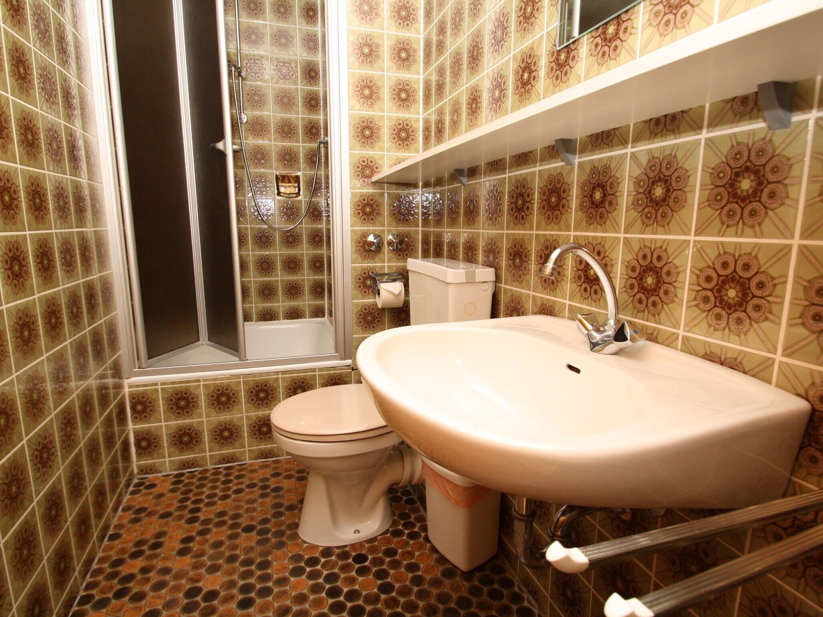 A bathroom with a toilet, sink, and shower.