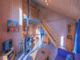A wooden interior with a TV, fireplace, sofa, and staircase.