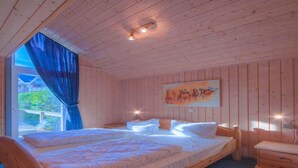 A wooden cabin bedroom with a bed, a nightstand, and a painting on the wall. - Exclusive Skandinavisches, Rechlin (Rechlin)
